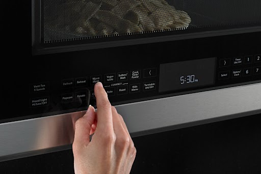 Deux poitrines de poulet crues sur une assiette dans un four à micro-ondes Whirlpool.