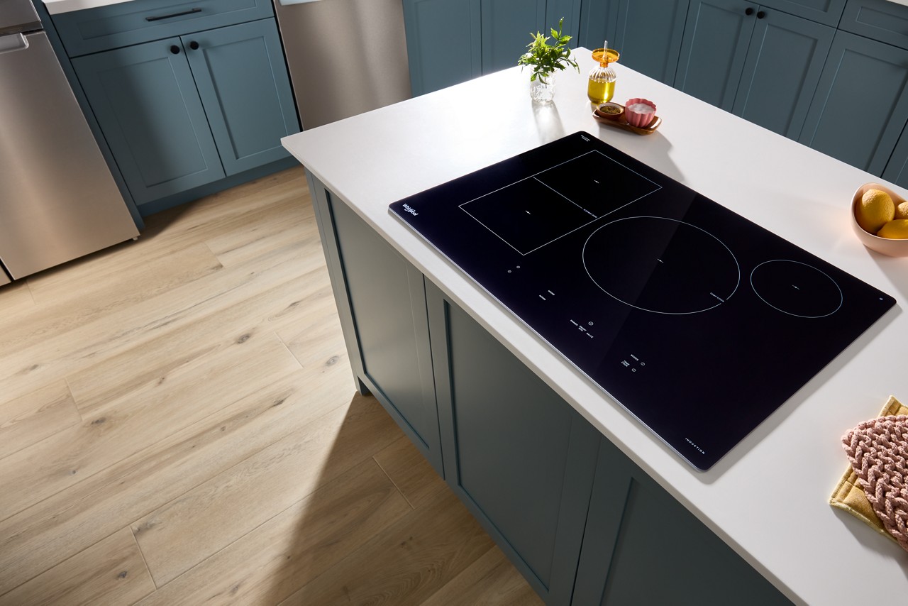 Electric cooktop installed on white countertop in blue cabinetry