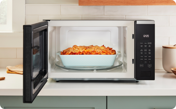 An opened Whirlpool Microwave with a casserole on the turntable