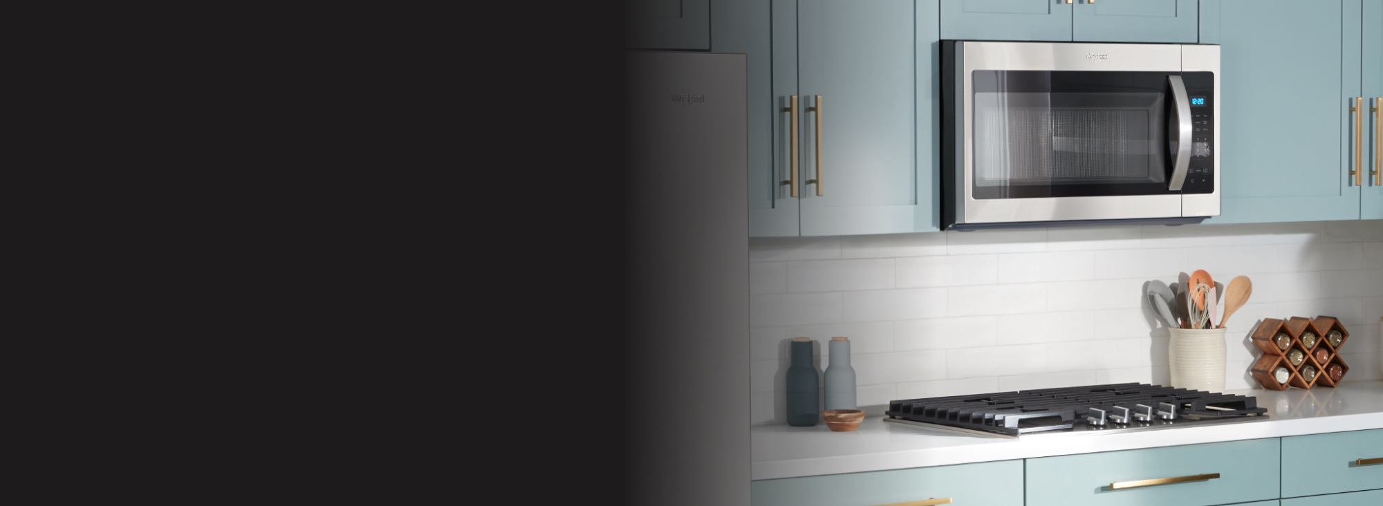 Un four à micro-ondes Whirlpool au-dessus d'une table de cuisson. Les appareils de cuisine sont entourés d'une étagère à épices, d'un porte-ustensiles, d'une salière et poivrière et d'un petit bol en bois