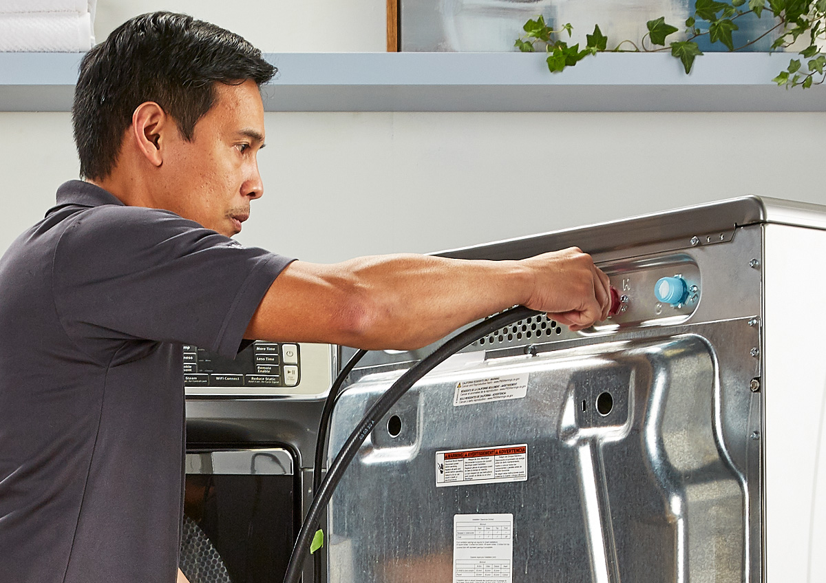  A uniformed repairman services a laundry appliance