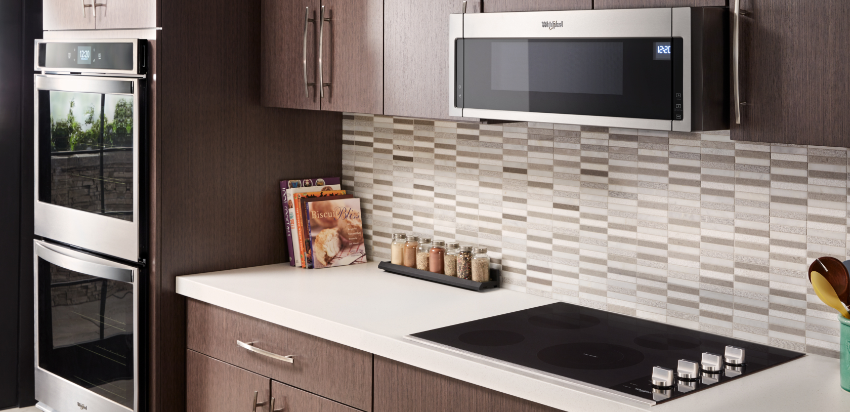 A kitchen with a Whirlpool Cooktop, a Whirlpool Over-the-Range Microwave and a Whirlpool Double Wall Oven. On the counters are cookbooks and a tray of spices