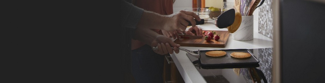 Une personne retourne des crêpes sur une table de cuisson à induction
