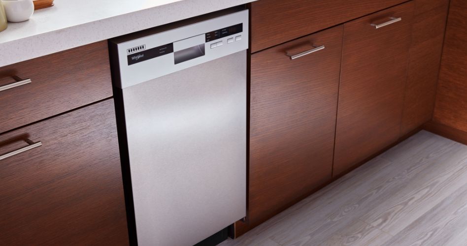 A kitchen with wood cabinets and drawers surrounding a Whirlpool dishwasher.