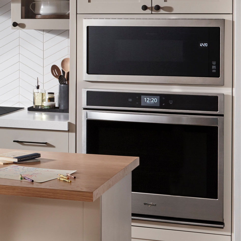 Un four mural double en acier inoxydable Whirlpool encastré dans une armoire de cuisine.