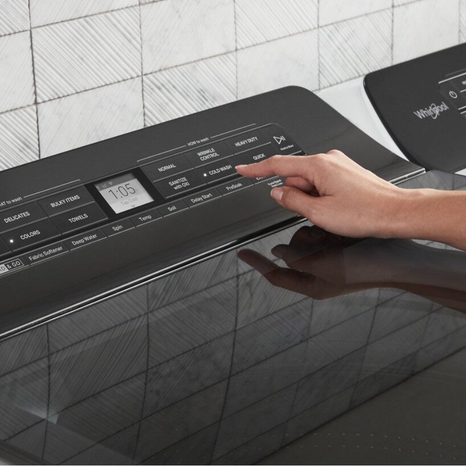 Someone selecting a setting on the black control panel of a washing machine.