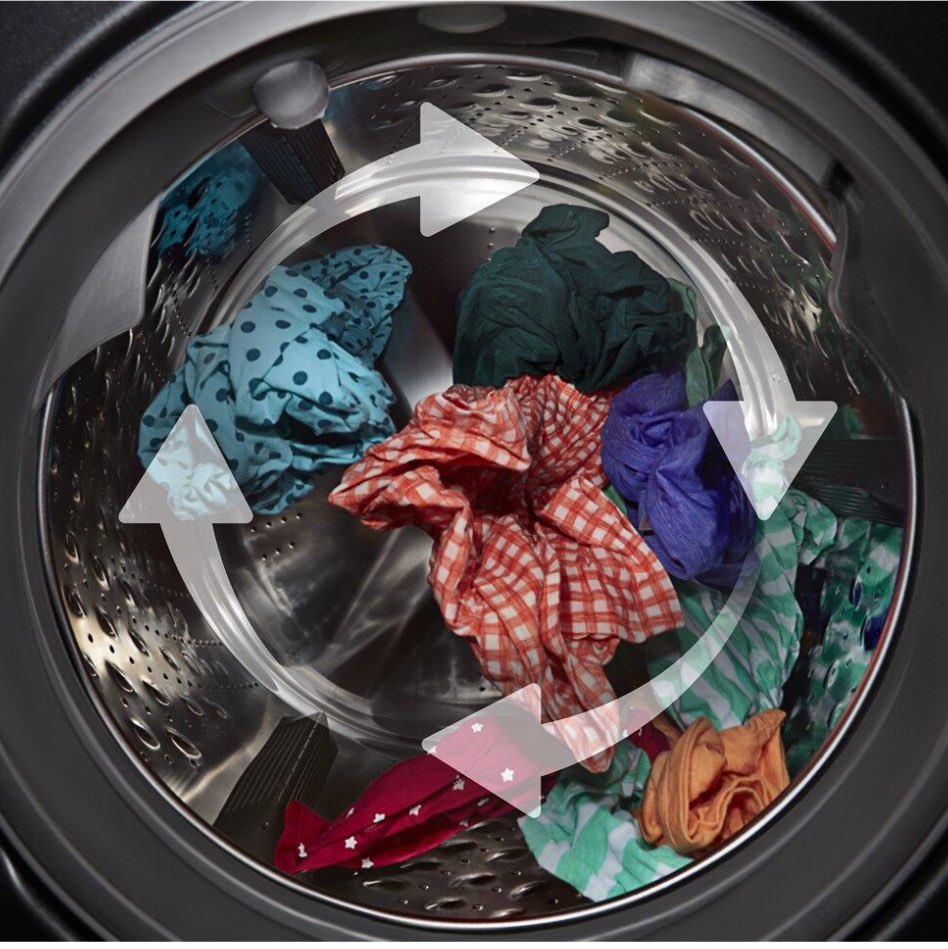 Through the window on the washing machine door: white arrows indicating that clothes of various colours are turning as they are being washed.