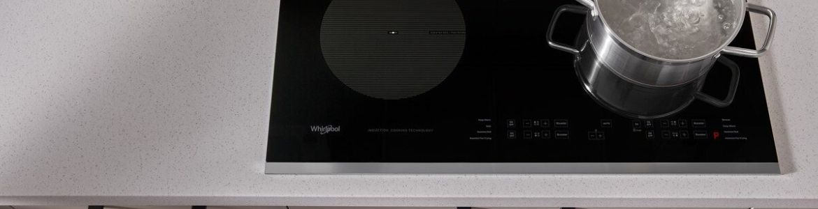 A kitchen with a Whirlpool Induction Oven and white cabinets and drawers. On the counter are a mail holder, a bottle of oil and a salt and pepper shaker.