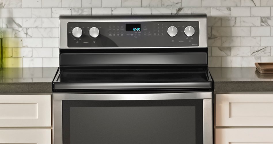 Une cuisinière à induction Whirlpool entre deux comptoirs/armoires. Sur le comptoir se trouvent une bouteille d'huile, une salière et une autre bouteille.