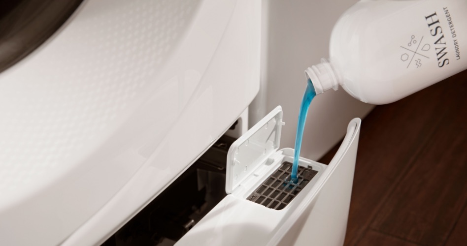 Une personne rempli le distributeur de détergent à lessive d'une laveuse frontale avec du détergent à lessive Swash