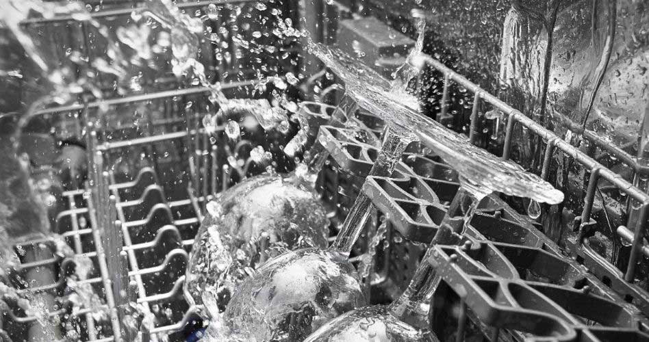 Inside a Whirlpool dishwasher that is in operation. Three glasses are being sprayed with water.