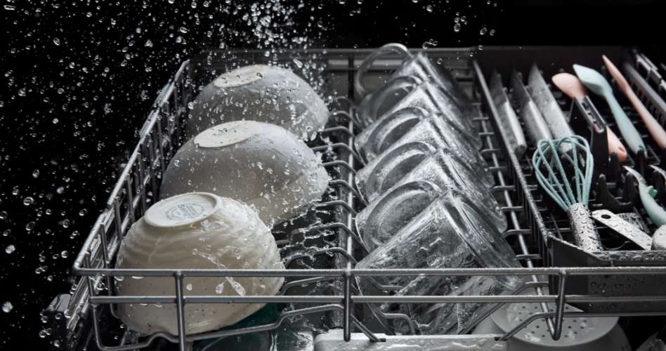 Whirlpool Combination Microwave Le panier supérieur d'un lave-vaisselle Whirlpool pendant un cycle de lavage. Sur le panier se trouvent des bols, des tasses, des couverts et quelques ustensiles de cuisine comme un fouet