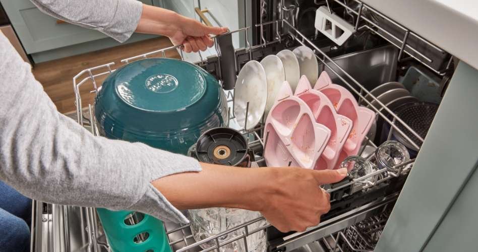 Whirlpool Combination Microwave Quelqu'un ajuste le positionnement d'un panier dans un lave-vaisselle Whirlpool. Sur le panier se trouvent un grand bol en céramique, des assiettes, des assiettes roses à plusieurs compartiments pour enfants et des verres