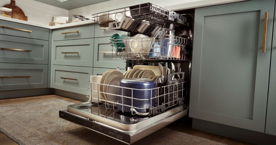 An opened Whirlpool Dishwasher with the racks pulled out. The racks are full of pots, plates, cups, mugs, bowls, and more. 