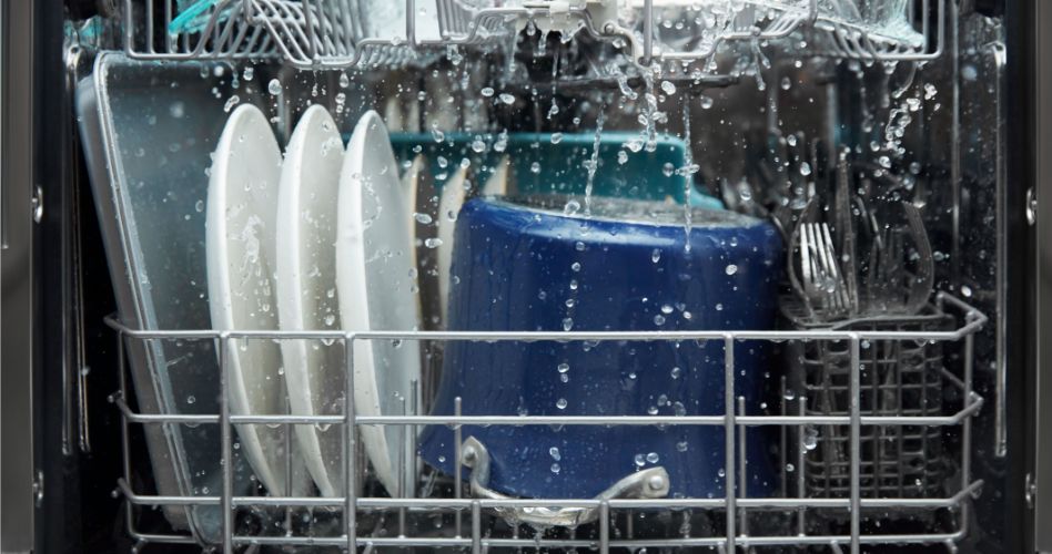 Whirlpool Combination Microwave Inside of a dishwasher that's in operation. Being washed on a rack are cutlery, a pot, plates and a baking sheet.