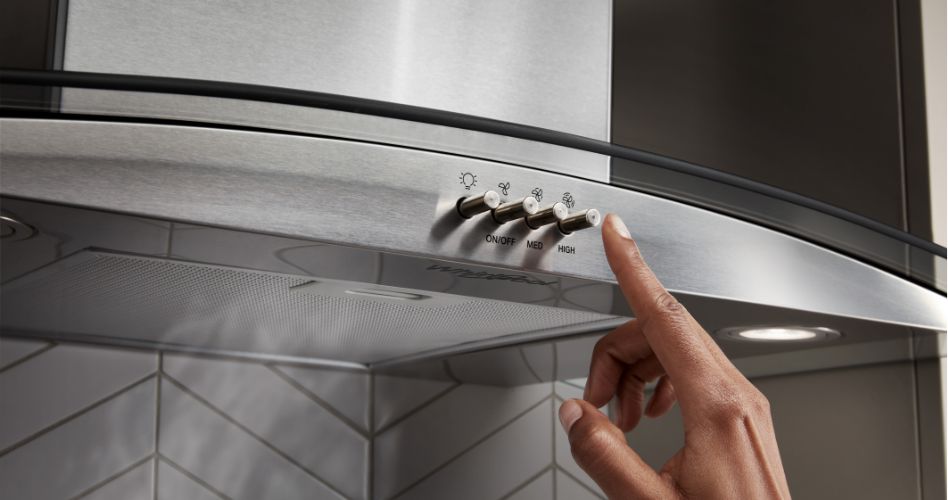 Whirlpool Combination Microwave Un doigt appuie sur le bouton d'une hotte de cuisine Whirlpool