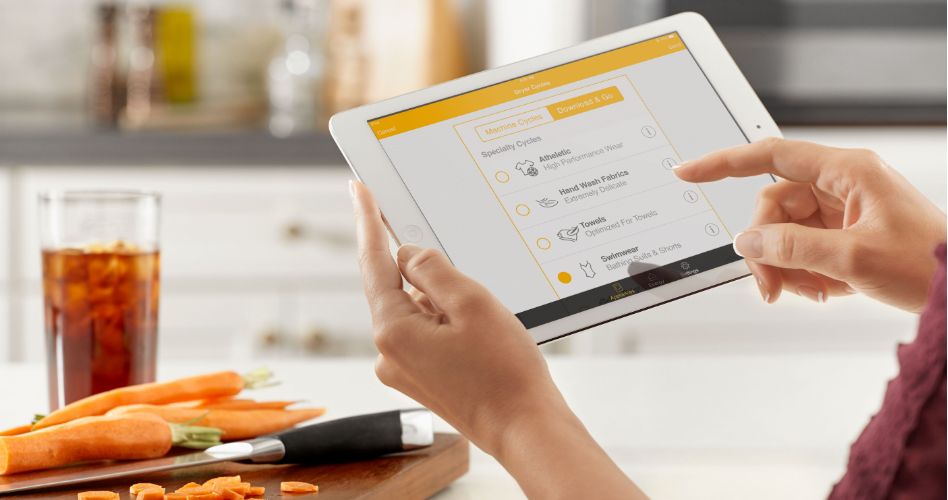 Whirlpool Combination Microwave Someone using the Whirlpool app on a tablet. In front of them is a glass of beverage and a cutting board with carrots and knife on top.