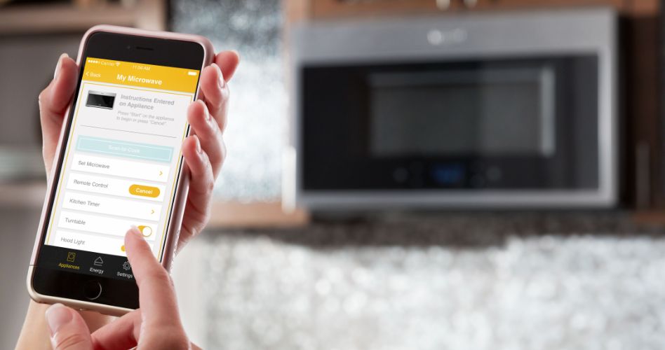 Whirlpool Combination Microwave Someone holding a smartphone that's open to the Whirlpool app. In the background is a Whirlpool over-the-range microwave.