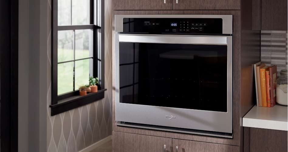 Whirlpool Combination Microwave Un four mural simple Whirlpool en acier inoxydable encastré dans une armoire près d'une fenêtre de cuisine