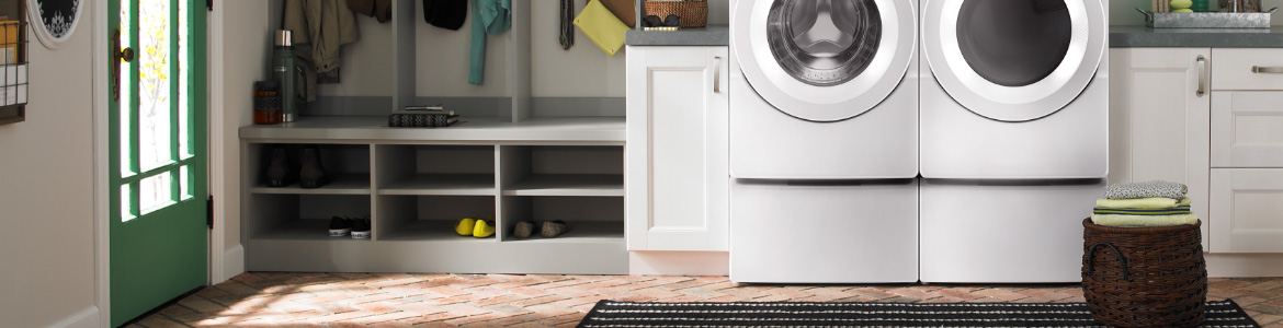 Laveuse et sécheuse blanches à chargement frontal Whirlpool sur un piédestal.