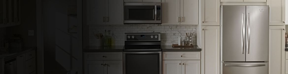 A modern kitchen featuring a stainless steel Whirlpool refrigerator, microwave, and range