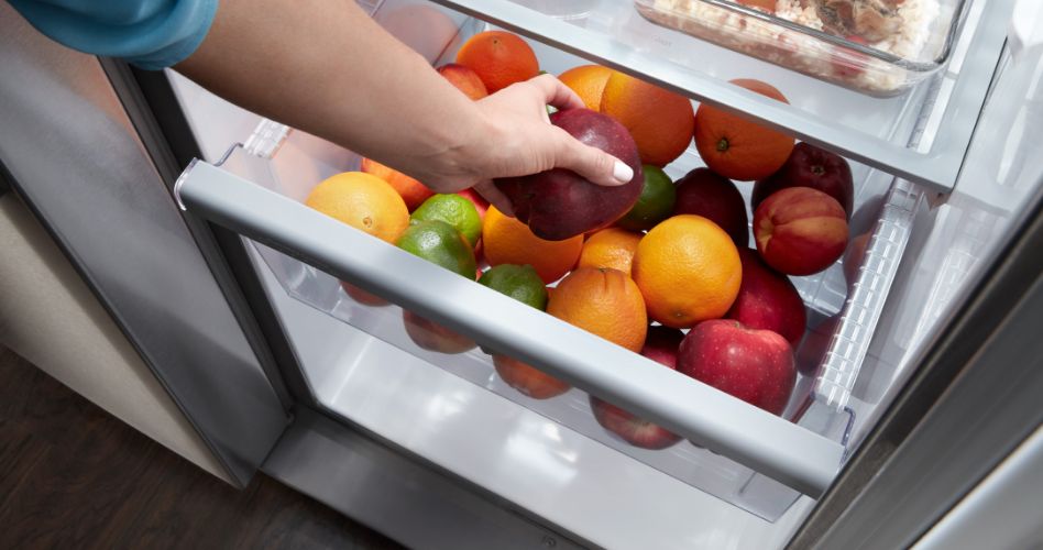 Une variété de fruits est conservée dans le tiroir à légumes d'un réfrigérateur