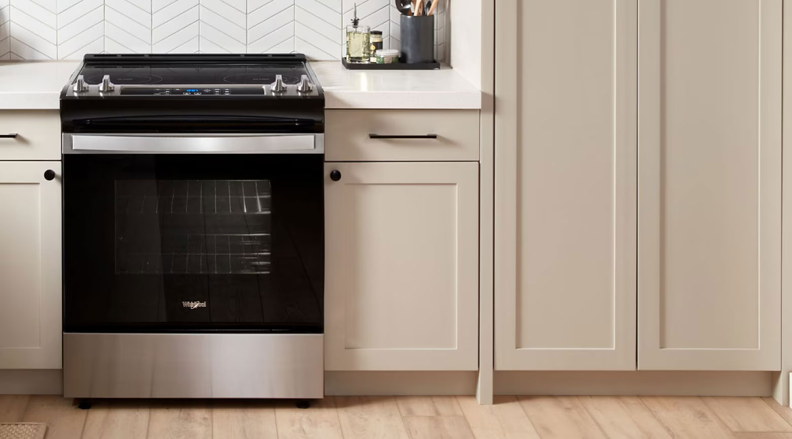 Whirlpool Combination Microwave Une cuisine équipée d'un four Whirlpool. Sur les comptoirs se trouvent, entre autres, un récipient à huile et un porte-ustensiles de cuisine.