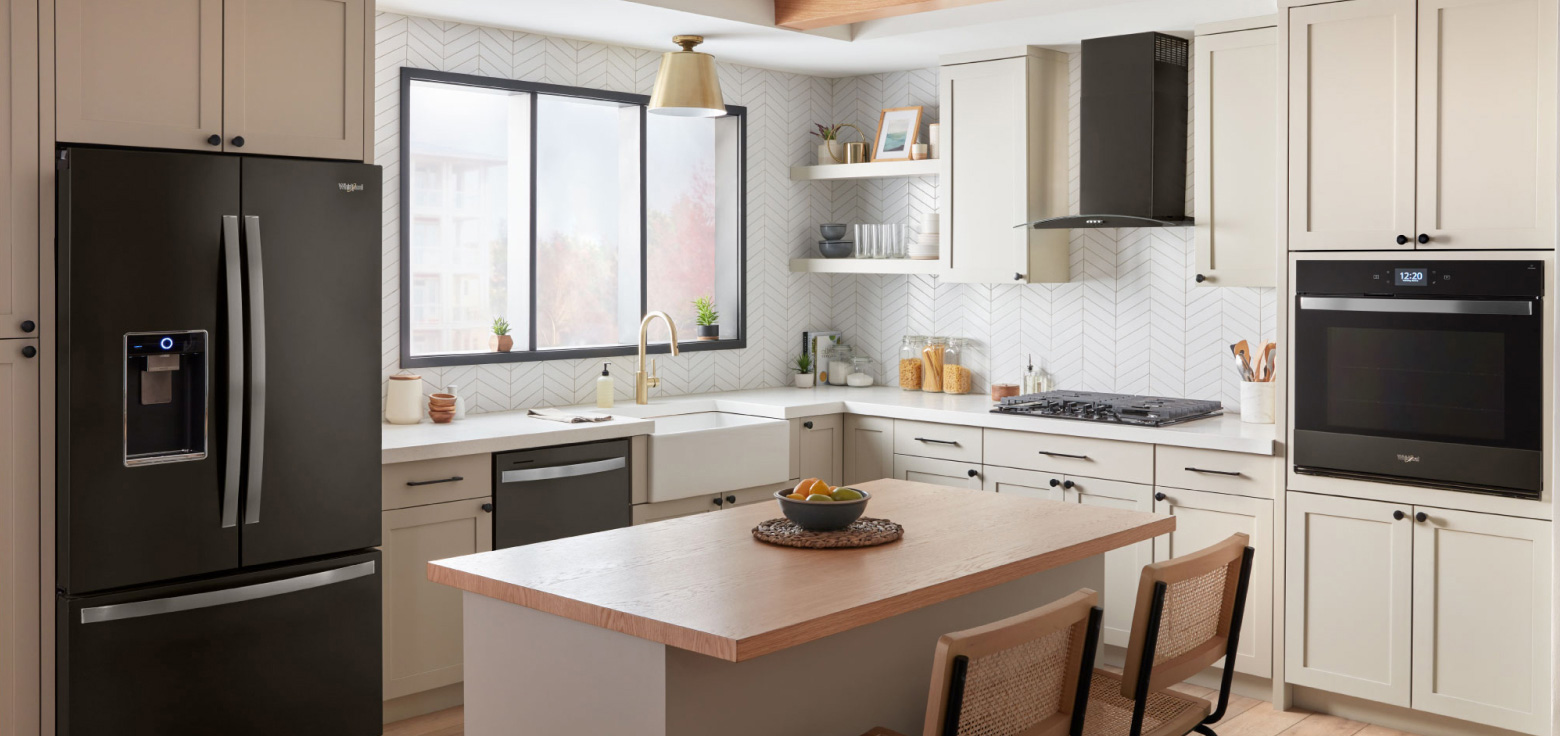Une cuisine lumineuse avec des appareils électroménagers en acier inoxydable et des armoires de couleur crème Une cuisine lumineuse avec des appareils électroménagers en acier inoxydable et des armoires de couleur crème