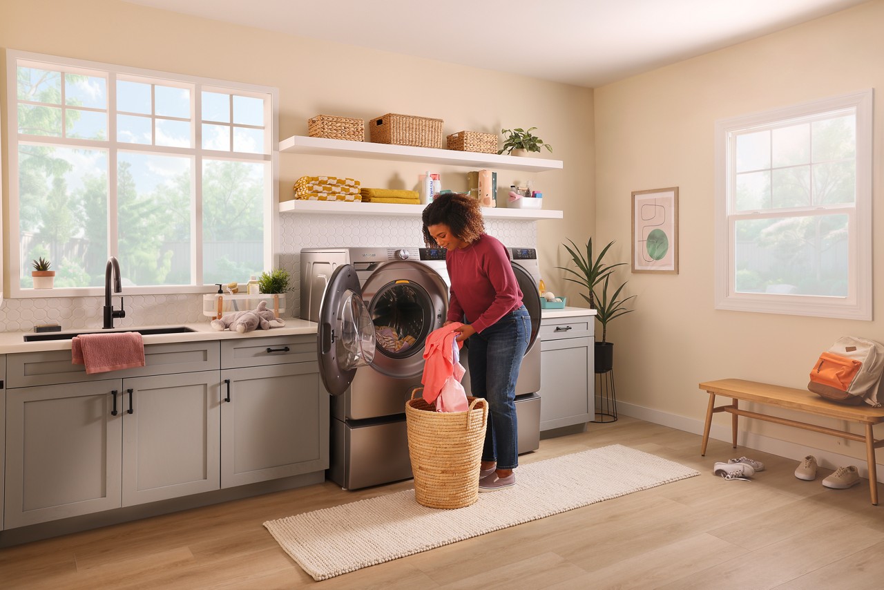 Une femme retire un vêtement d’un panier et le place dans une laveuse Whirlpool®.