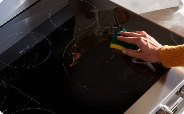 Quelqu’un frotte la surface de cuisson d’une cuisinière Whirlpool avec une éponge