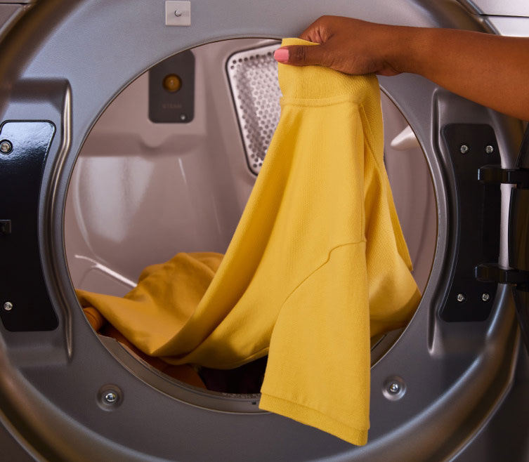 A person taking clothes out of a Whirlpool® Dryer