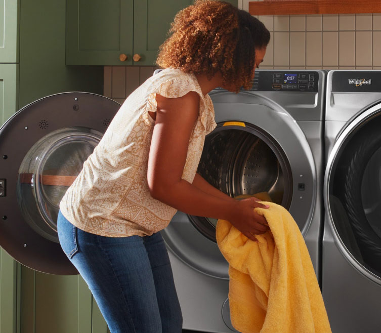 A person loading laundry into a Whirlpool® Washer