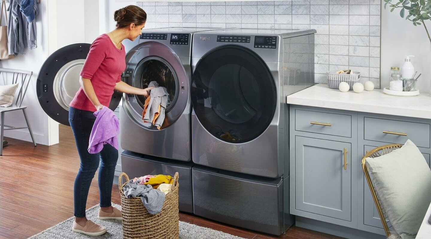 Une personne place des vêtements dans une sécheuse Whirlpool® à chargement frontal