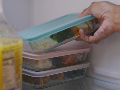 A person placing leftovers in the fridge