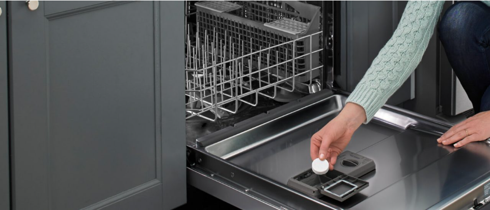 A person adding a dishwasher cleaner tablet to a dishwasher Une personne ajoute une pastille de nettoyant pour lave-vaisselle dans un lave-vaisselle.