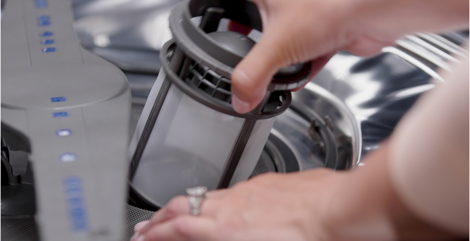 Une personne retire le filtre d'un lave-vaisselle