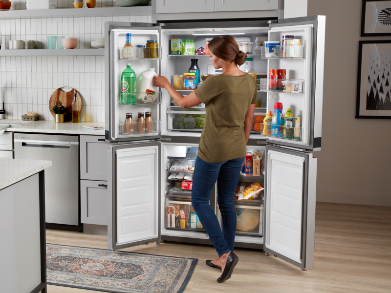 Person removing things from a 4-door refrigerator Person removing things from a 4-door refrigerator