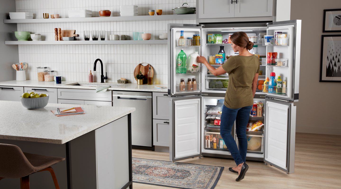 Personne retirant des objets d'un réfrigérateur à 4 portes Personne retirant des objets d'un réfrigérateur à 4 portes