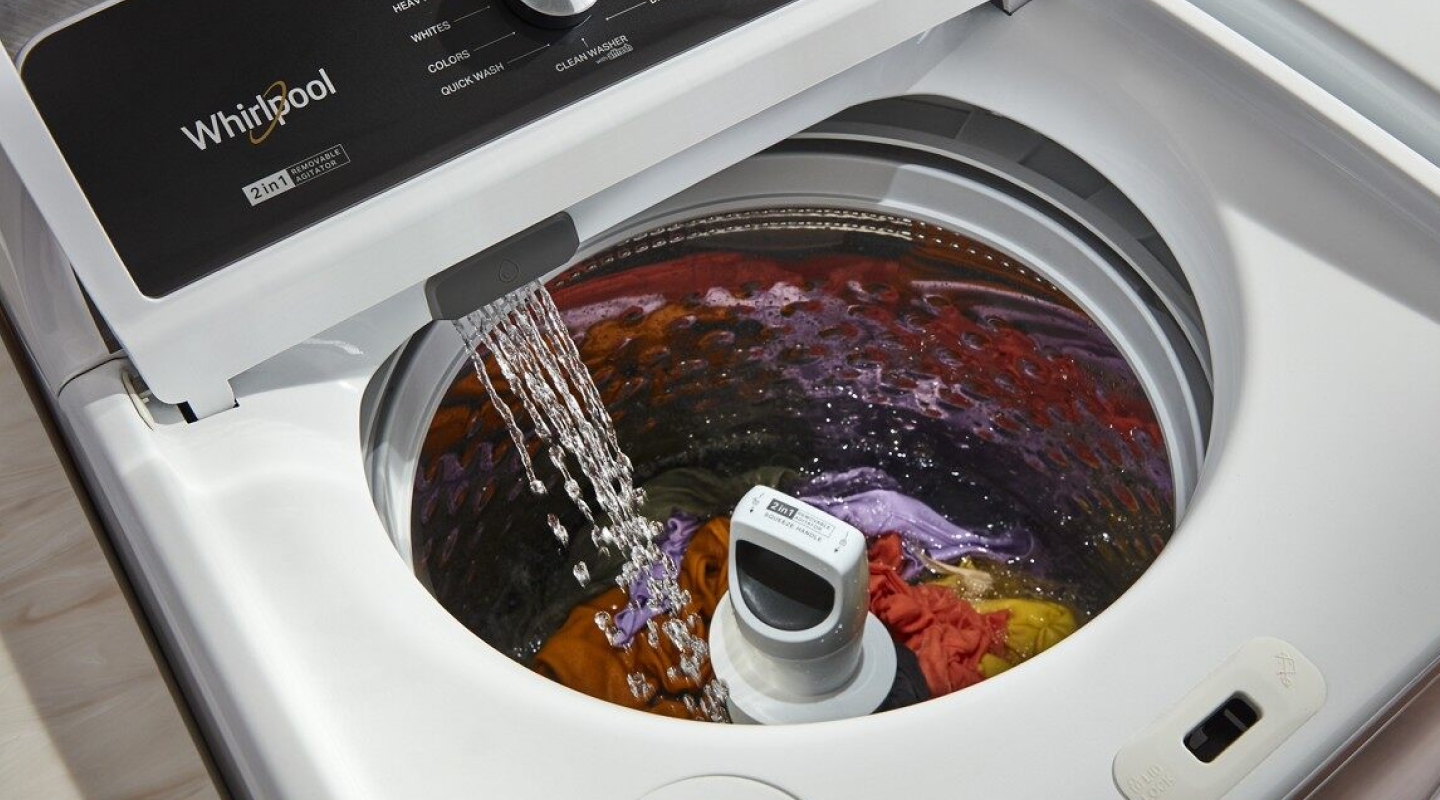 A closeup of a Whirlpool® top load washing machine filling with water.