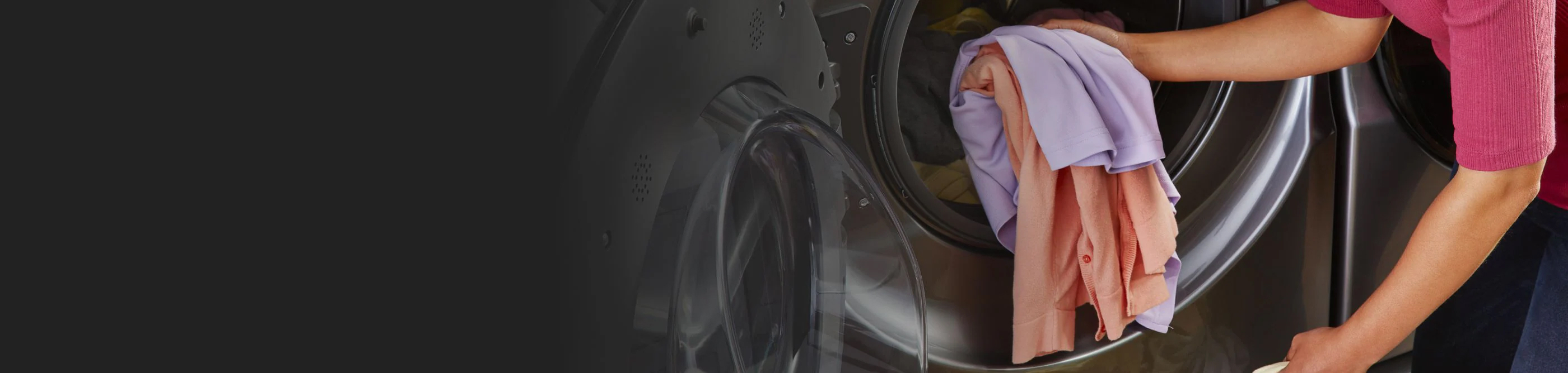 A person places some articles of clothing in a Whirlpool Front-Load Washer