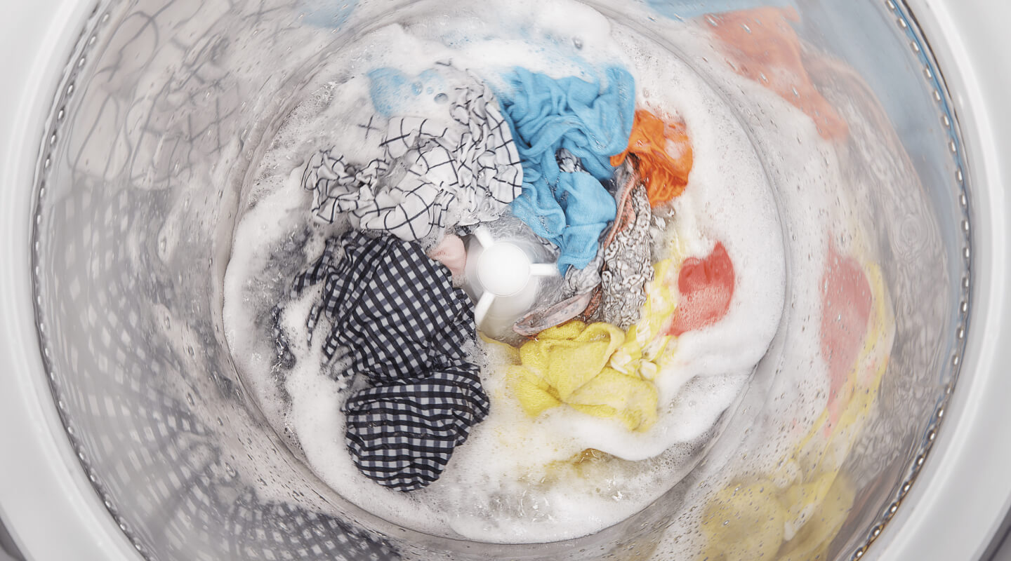 A load of clothes soaking inside a white washing machine