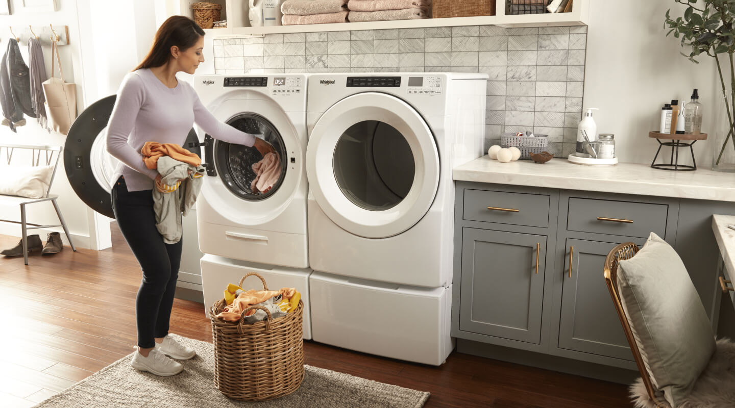 Person adding clothes to a white front load Whirlpool® Washer
