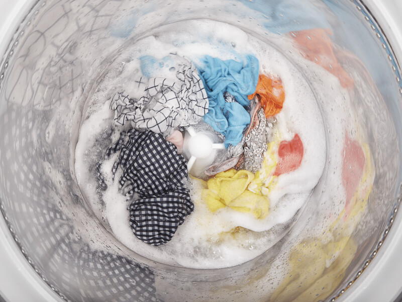 A load of clothes soaking inside a white washing machine