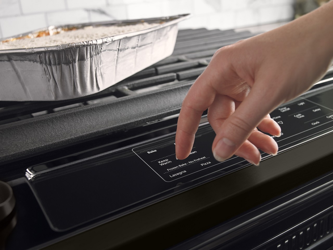 A person selects an oven cycle from a control panel. A person selects an oven cycle from a control panel.