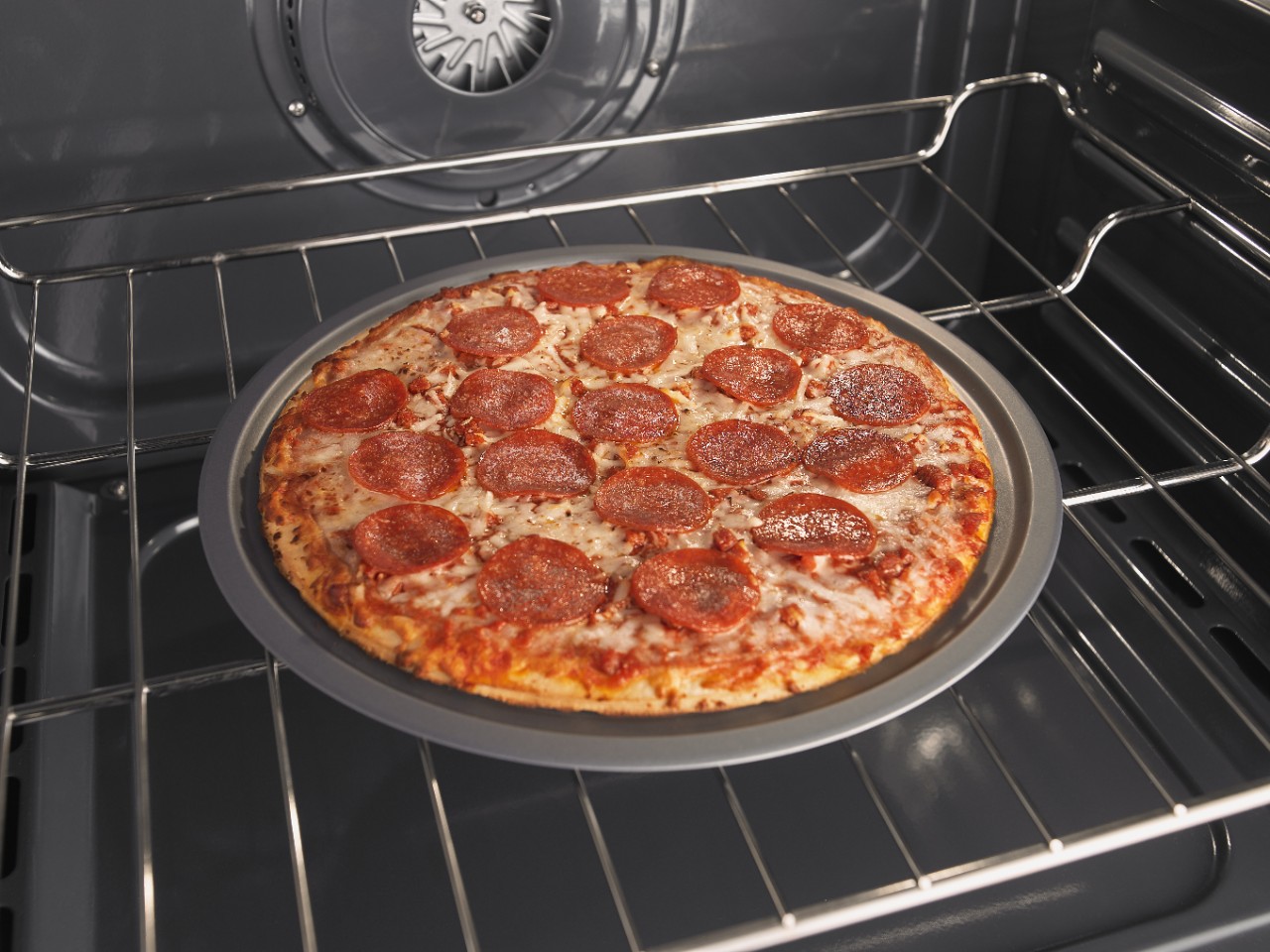 Pepperoni pizza baking in an oven.