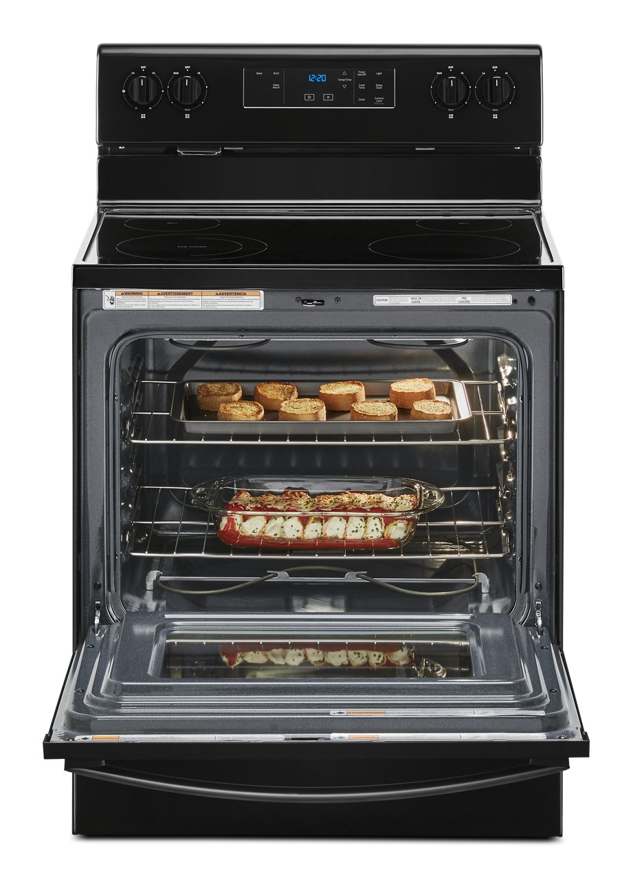 An open range with baked pasta and garlic bread inside. An open range with baked pasta and garlic bread inside.