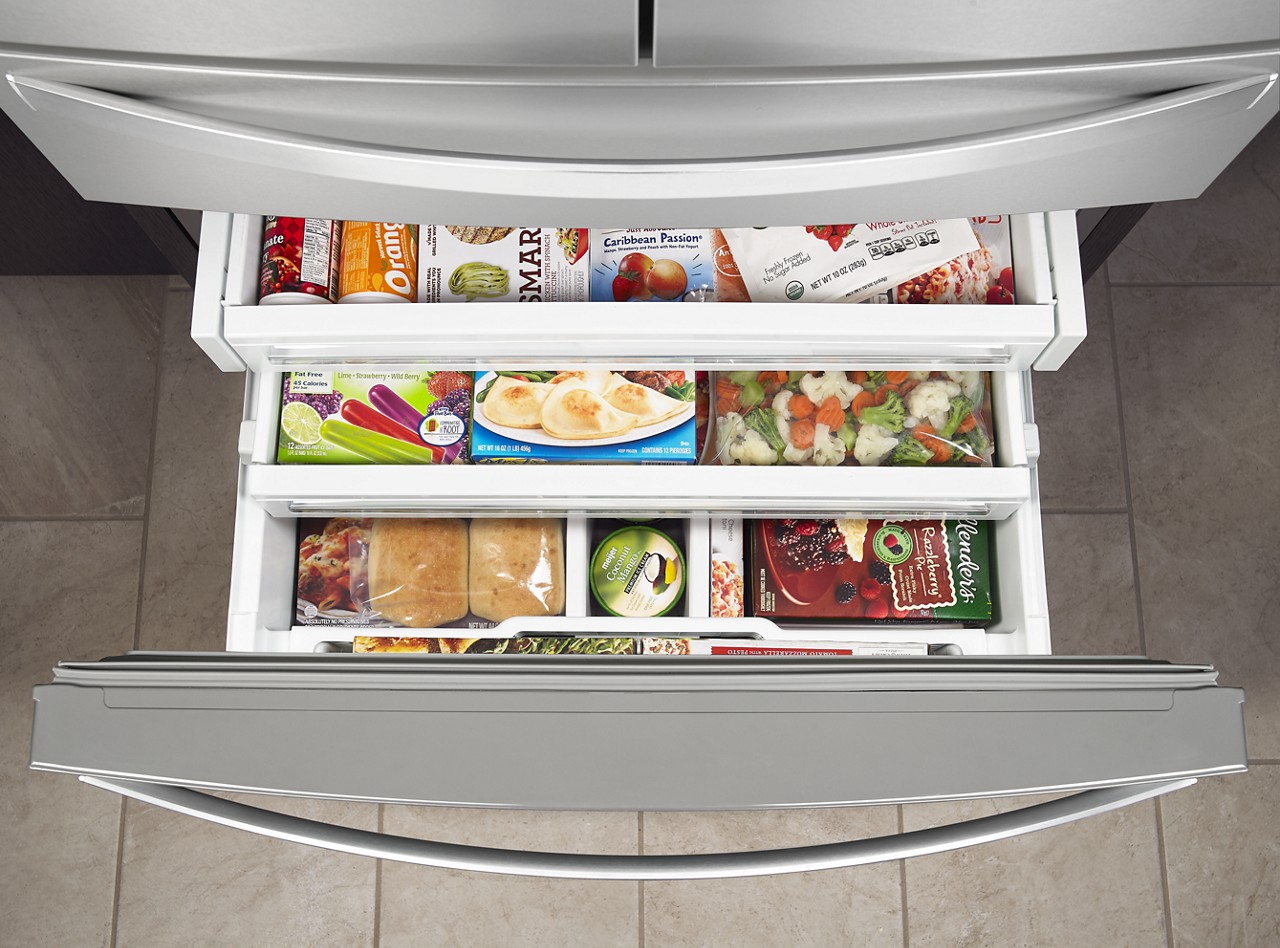 An open bottom freezer drawer full of food.