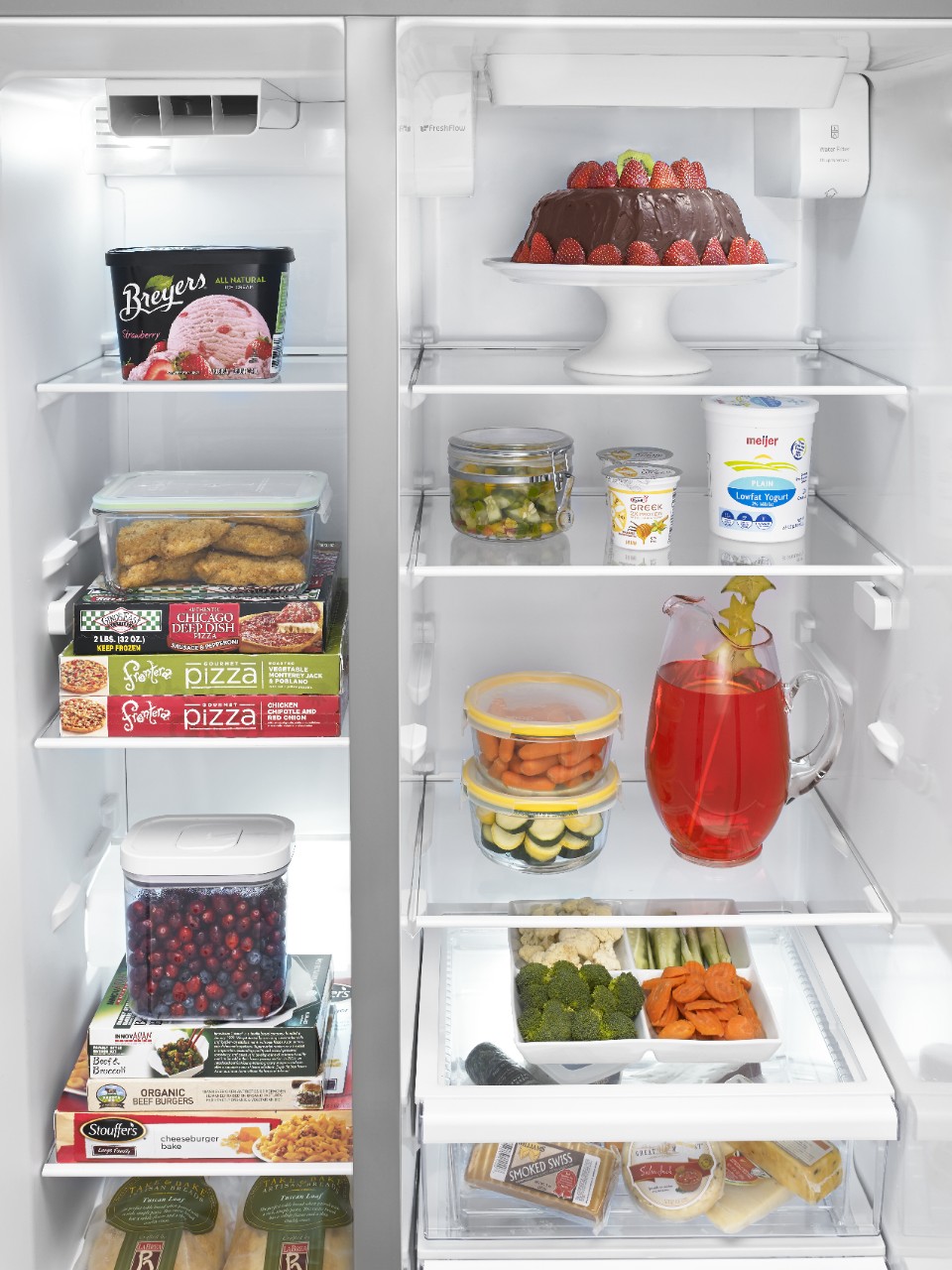 An open refrigerator displays numerous frozen and fresh foods. An open refrigerator displays numerous frozen and fresh foods.