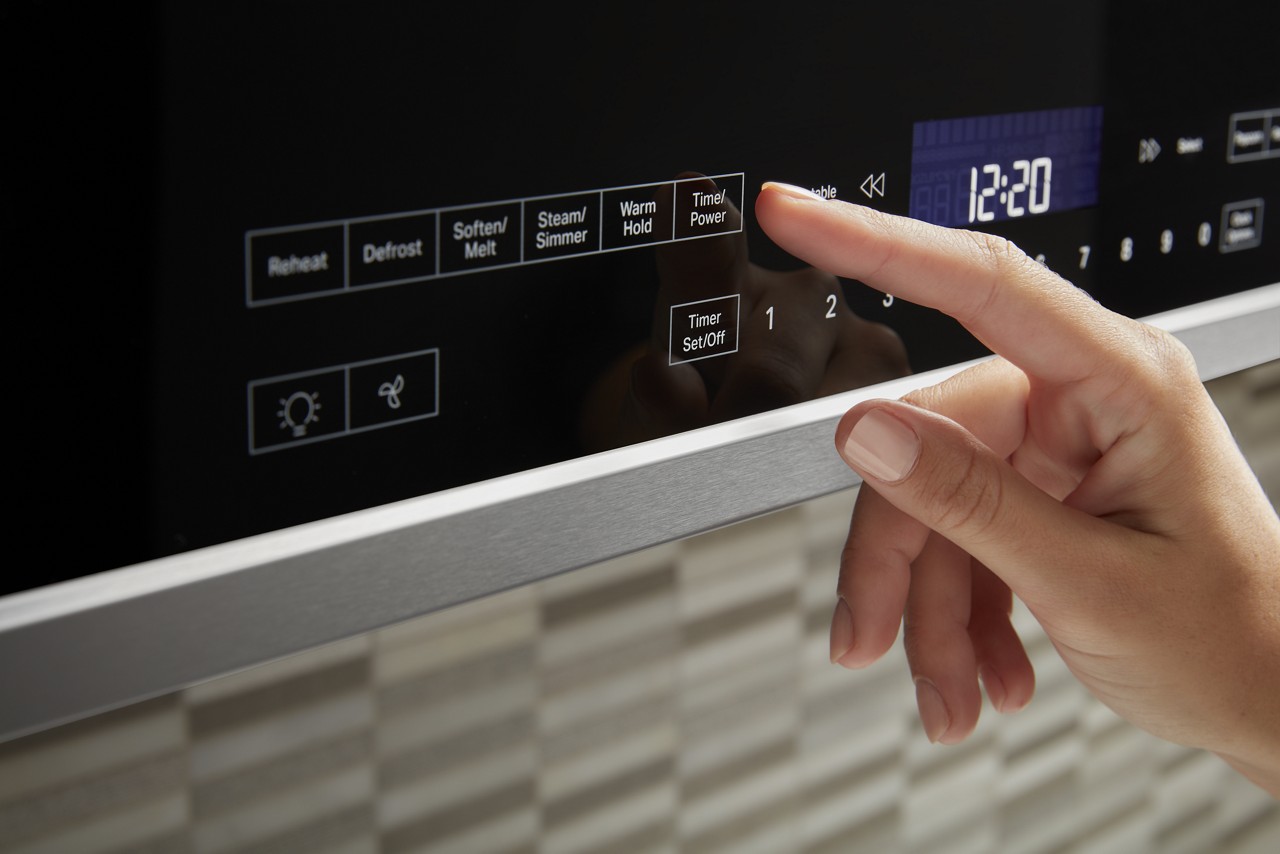 A person selects a microwave setting from a control panel.