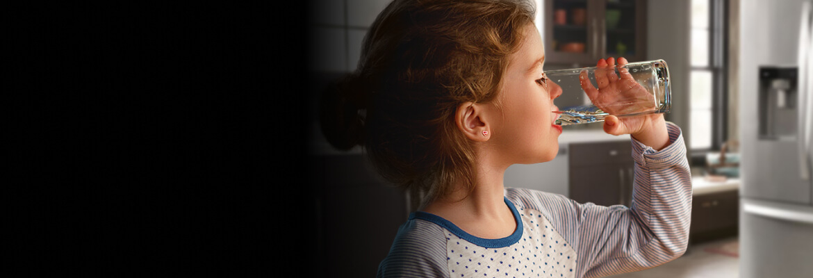 Young girl drinking a glass of water.